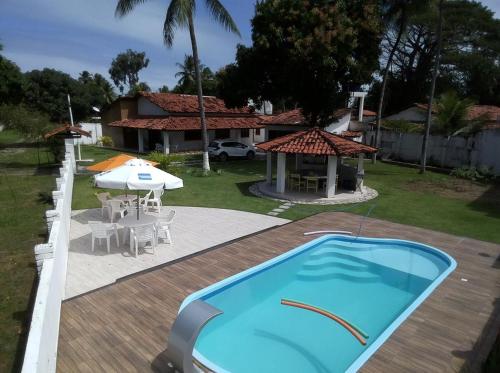 a swimming pool with a table and an umbrella and a house at Casa com piscina em Vera Cruz in Vera Cruz de Itaparica