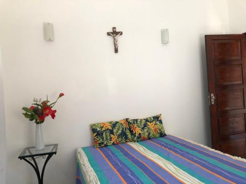 a bedroom with a bed and a cross on the wall at Casa com piscina em Vera Cruz in Vera Cruz de Itaparica