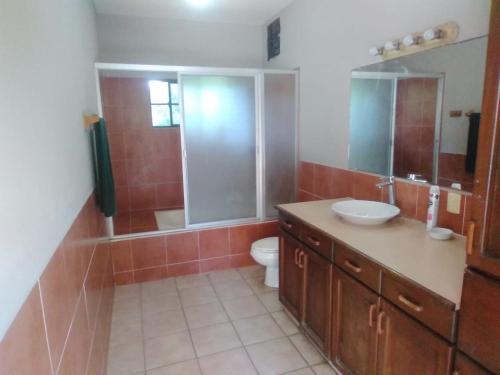 a bathroom with a sink and a toilet and a mirror at Beach On The Rocks in El Zonte