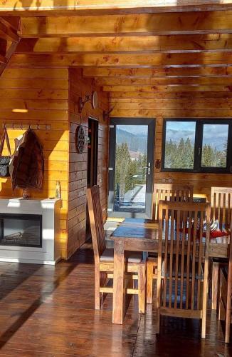 a wooden dining room with a table and a fireplace at Cabana Corbilor The Raven's Hut in Vatra Dornei