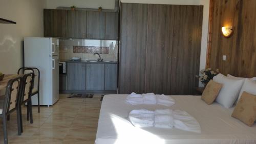 a bedroom with a white bed and a kitchen at Kanali Beach House in Kanali