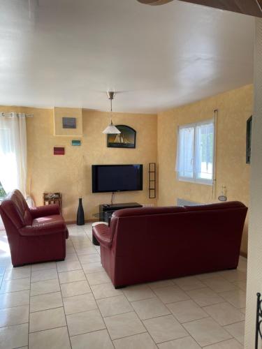 - un salon avec deux canapés rouges et une télévision à écran plat dans l'établissement Gite des galets, à Saint-Léonard