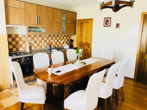 uma cozinha com uma mesa de madeira e cadeiras brancas em Kuća za odmor Mirna em Cepidlak