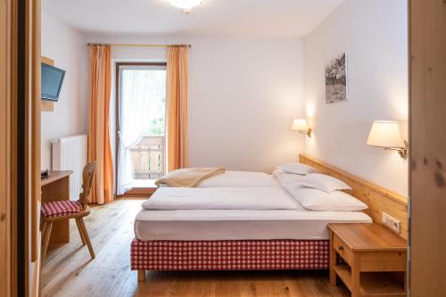 a hotel room with a bed and a window at Hotel Falken in Falzes