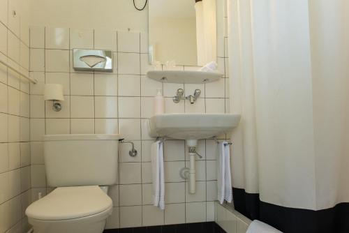 a small bathroom with a toilet and a sink at Jungfrau Hotel Annex Alpine-Inn in Wilderswil