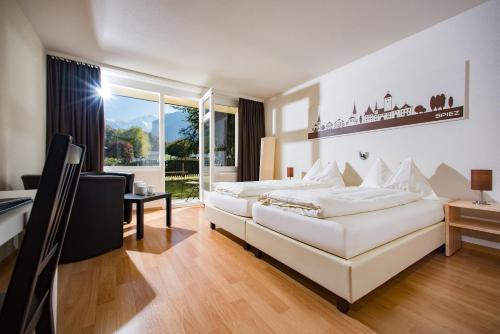 Un dormitorio con una gran cama blanca y una ventana en Jungfrau Hotel Annex Alpine-Inn, en Wilderswil