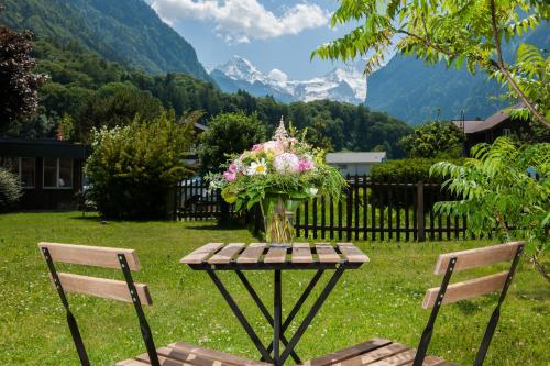 a vase of flowers on a table with two chairs at Jungfrau Hotel Annex Alpine-Inn in Wilderswil