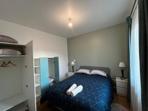 Appartement T2 Paray vieille poste في Paray-Vieille-Poste: غرفة نوم بسرير ازرق عليها مناشف