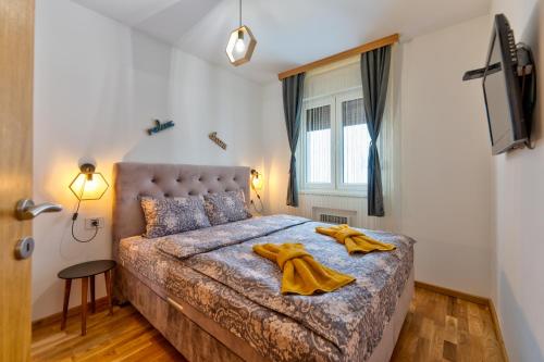 Un dormitorio con una cama con toallas amarillas. en Apartman Relja Zlatibor, en Zlatibor
