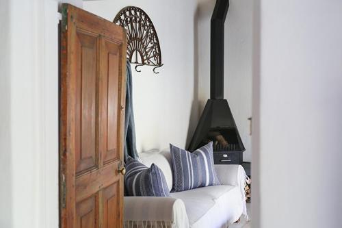 a white couch with blue pillows next to a stove at Dennehof Karoo Guesthouse in Prince Albert