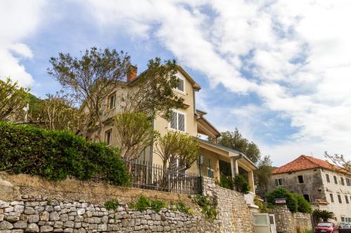a white house behind a stone wall at Apartmani Vesna in Tivat