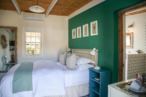 a bedroom with a white bed and a green wall at Dennehof Karoo Guesthouse in Prince Albert