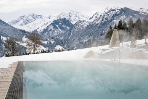 a swimming pool with snow covered mountains in the background at Gut Sonnberghof in Mittersill