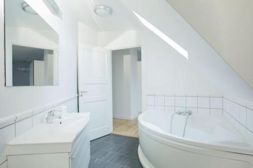 ein weißes Badezimmer mit einer Badewanne und einem Waschbecken in der Unterkunft Cozy 3BR Lake View Flat w Bath Tub in Copenhagen in Kopenhagen