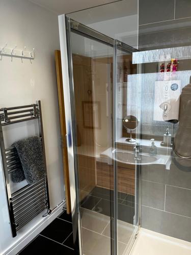 um chuveiro com uma porta de vidro na casa de banho em Lesanne Cottage em Inverness