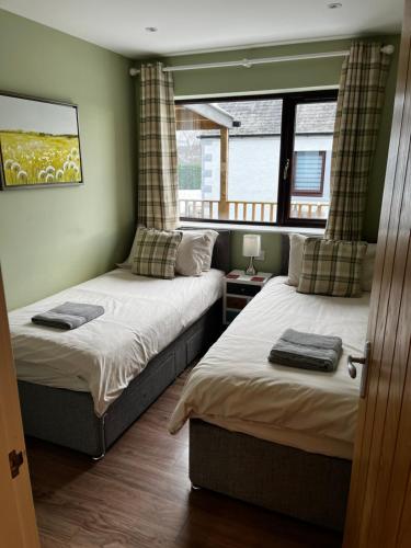 1 dormitorio con 2 camas y ventana en Lesanne Cottage en Inverness