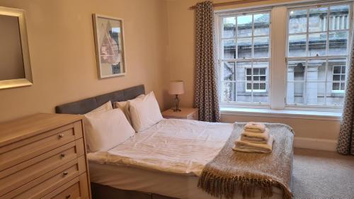 a bedroom with a bed with a dresser and a window at 4 New Assembly Close - Royal Mile in Edinburgh