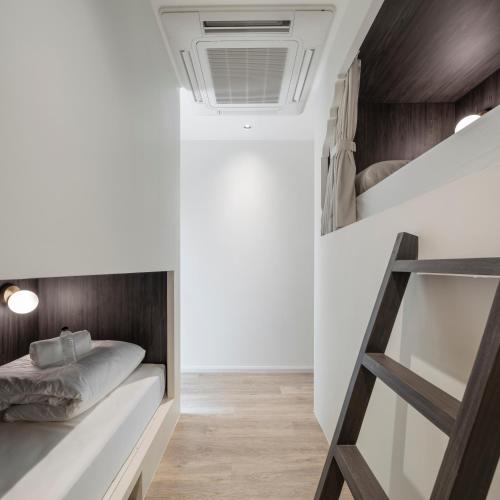 a small bedroom with a bunk bed and wooden floors at Lilit Bang Lumphu Hotel in Bangkok