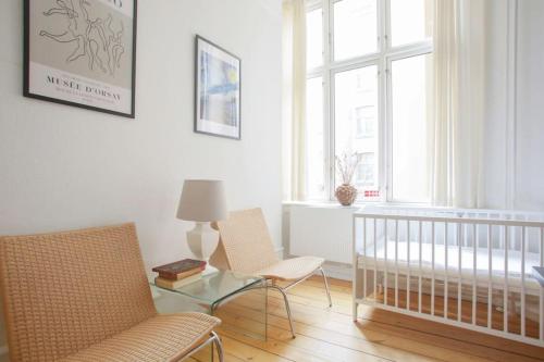 - une chambre avec un lit bébé, deux chaises et une table dans l'établissement Large & Bright 3BR Flat w Whirlpool Near Metro, à Copenhague