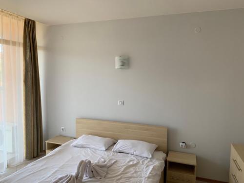 Schlafzimmer mit einem Bett mit weißer Bettwäsche und Kissen in der Unterkunft Апартамент с една спалня 521,Aparthotel Poseidon in Sonnenstrand