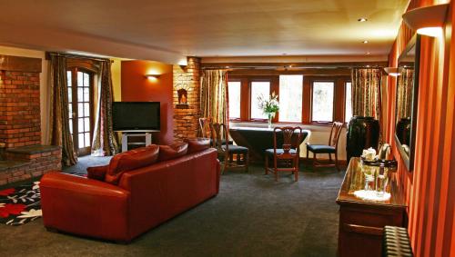 a living room with a red couch and a table at Gibbon Bridge Hotel in Clitheroe