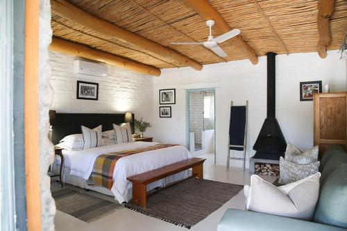 a bedroom with a large bed and a fireplace at Dennehof Karoo Guesthouse in Prince Albert