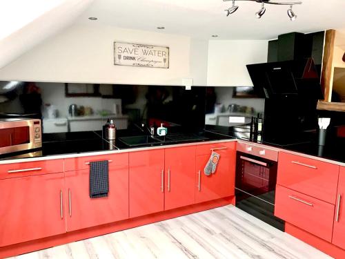 - une cuisine avec des placards rouges et un évier dans l'établissement LE CHAMPENOIS, Avenue de Champagne, à Épernay