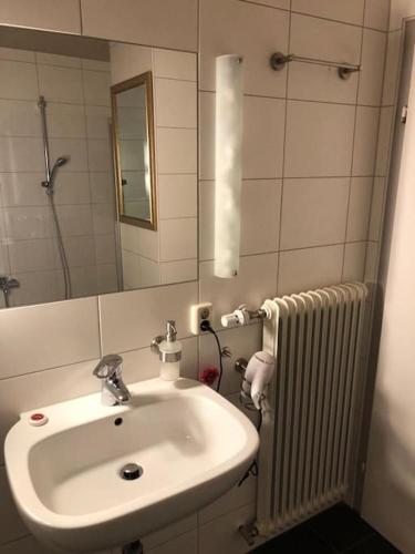 a bathroom with a sink and a mirror and a radiator at Superschöne Ferienwohnungen! in Buxheim