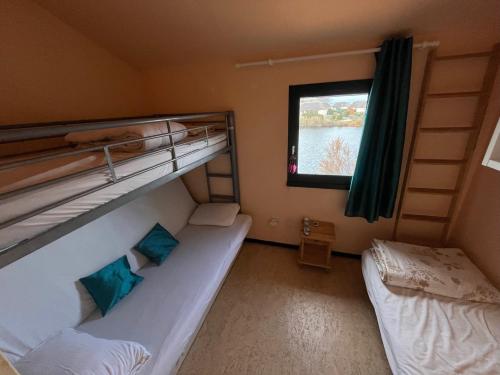 deux lits superposés dans une chambre avec fenêtre dans l'établissement Maison à Coudalère, entre étang et mer !, au Barcarès