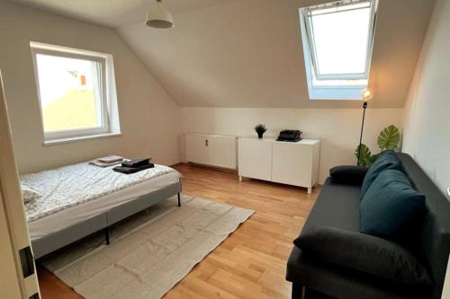 a bedroom with a bed and a couch and two windows at Cozy City Center Apartment in Graz