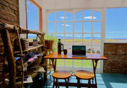 a table with a laptop on it in front of a window at Hostel Aves del Lago in El Calafate