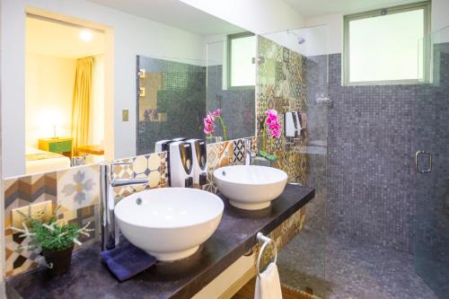 La salle de bains est pourvue d'un lavabo et d'une douche. dans l'établissement La Vela Boutique Hotel, à Manuel Antonio