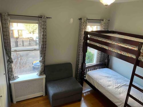 ein Schlafzimmer mit einem Etagenbett, einem Stuhl und einem Fenster in der Unterkunft Wonderful 2 Bedroom in the heart of Astoria in Steinway