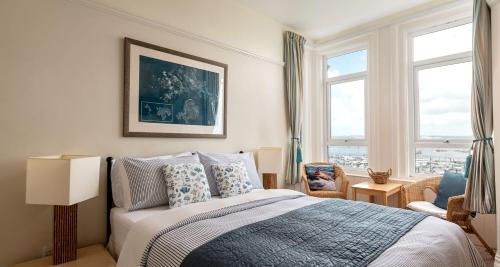 a bedroom with a bed and two windows at Marina View Brixham in Brixham