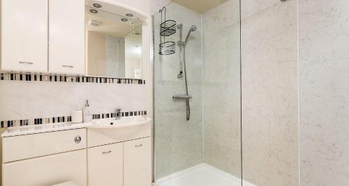 a white bathroom with a shower and a sink at Marina View Brixham in Brixham