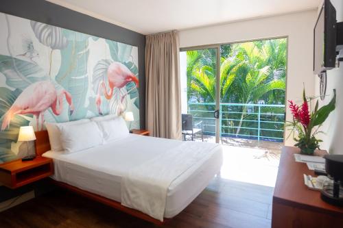 een slaapkamer met een bed en een groot raam bij La Vela Boutique Hotel in Manuel Antonio