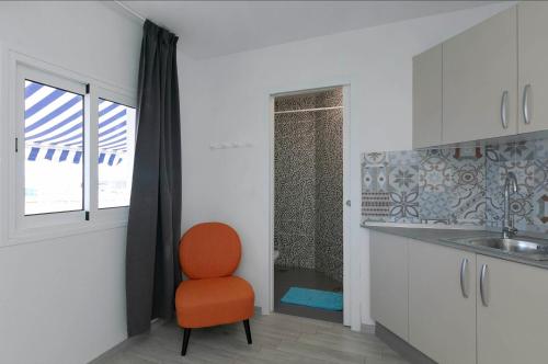 an orange chair in a kitchen with a sink at Sur Restinga in La Restinga