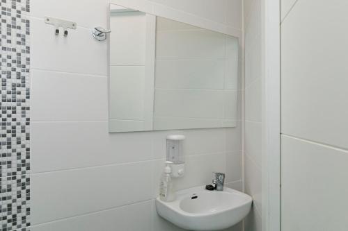 a white bathroom with a sink and a mirror at Sur Restinga in La Restinga
