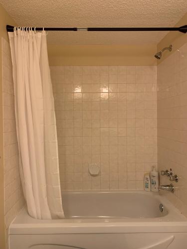 a bathroom with a bath tub with a shower curtain at MT Pleasant NW 2 bedrooms 502 in Calgary
