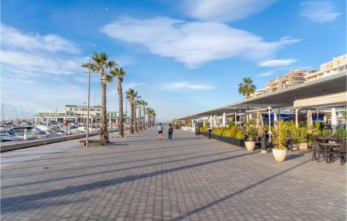 a boardwalk with palm trees and buildings on a beach at Beautiful Apartment In Santa Pola in Santa Pola