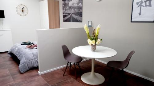 a table with two chairs and a vase with flowers on it at SKY LOFT Nuovissimo vicinanze Metro in Turin