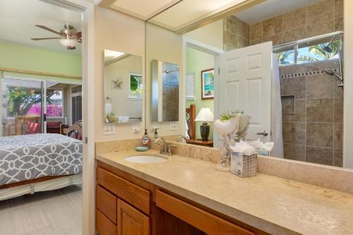 łazienka z umywalką, łóżkiem i lustrem w obiekcie Big Island Awamoa Hale home w mieście Waikoloa