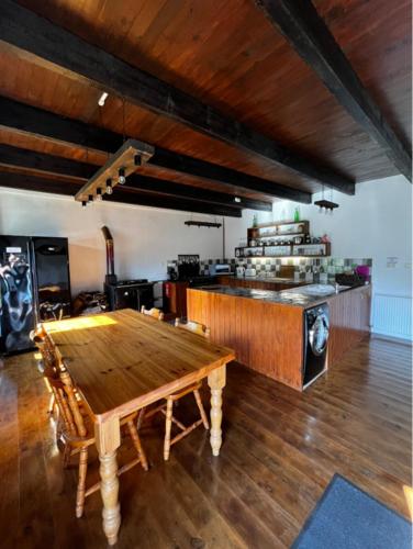 a room with a wooden table and a kitchen at Maison de Maison in Maël-Pestivien