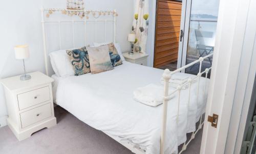 a white bedroom with a white bed and a mirror at Puffin 4 - The Cove in Brixham