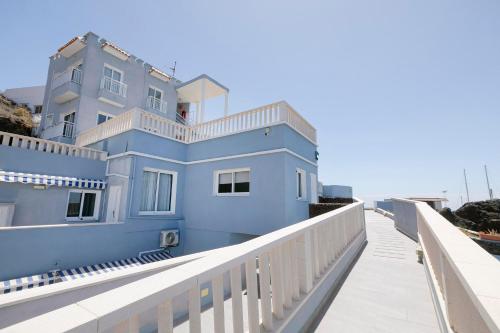 a blue building with a white fence next to it at Sur Restinga in La Restinga