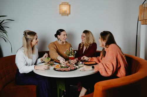 Hotel restaurant SAM في ثولين: جلوس اربع نساء حول طاولة مع صحن طعام