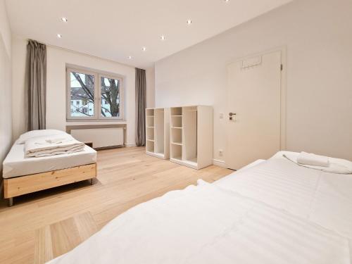 RAJ Living - 300m2 Loft with 7 Rooms - 15 Min Messe DUS & Old Town DUS في دوسلدورف: غرفة نوم بيضاء بسريرين ونافذة