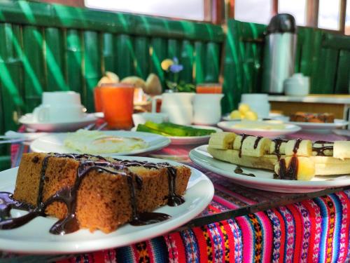 una mesa cubierta con platos de pastel y postres en Hostal Cusco Internacional, en Cusco