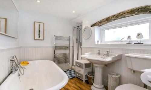 La salle de bains est pourvue de 2 lavabos, d'une baignoire et d'une fenêtre. dans l'établissement Sandy Bottom, à Brixham