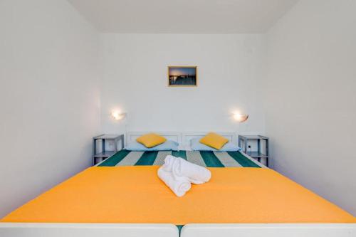 sypialnia z pomarańczowym łóżkiem i ręcznikami w obiekcie Povlja Bungalows w mieście Povlja